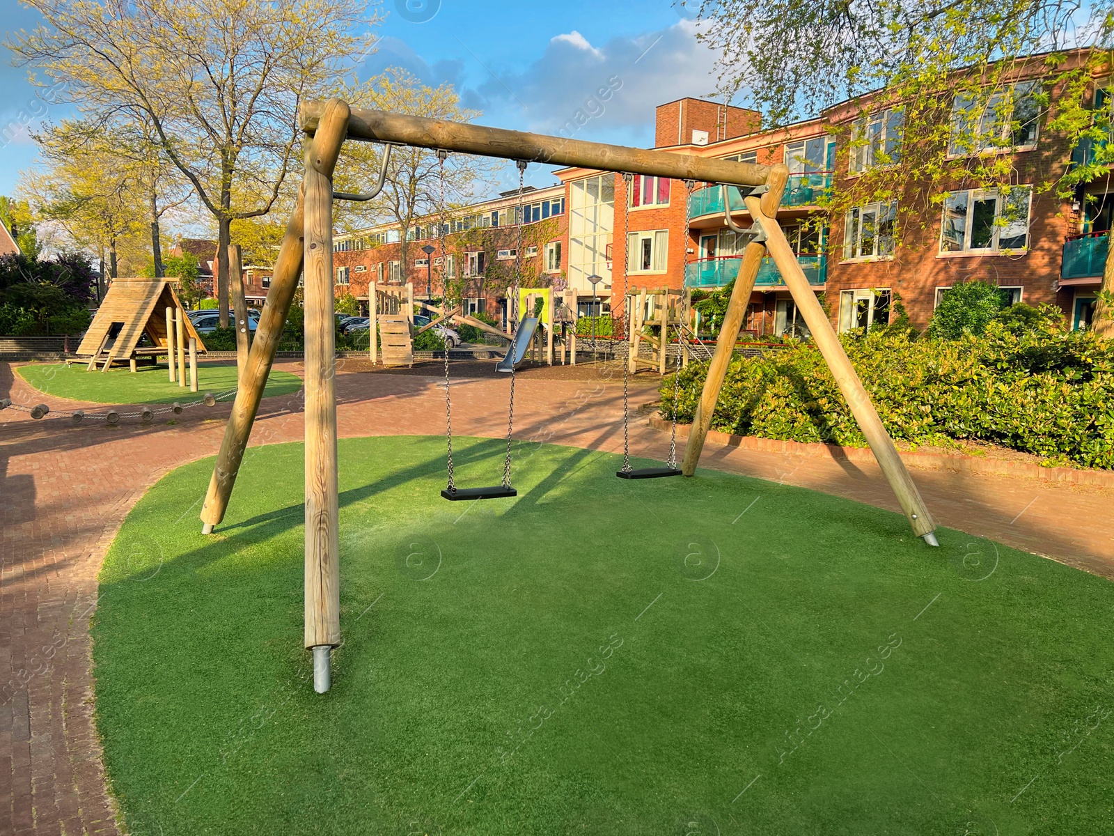 Photo of Outdoor playground for children with wooden swings on sunny day