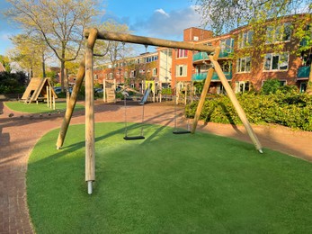 Photo of Outdoor playground for children with wooden swings on sunny day