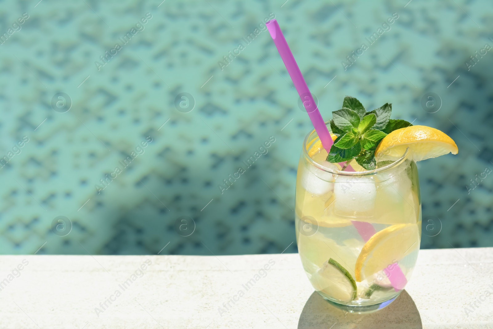 Photo of Refreshing drink with citrus slices and mint near swimming pool. Space for text