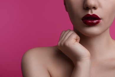 Closeup view of woman with beautiful full lips on pink background, space for text