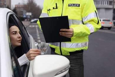 Photo of Woman giving bribe to police officer out of car window