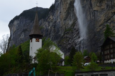 View of beautiful church, houses and waterfall in mountains