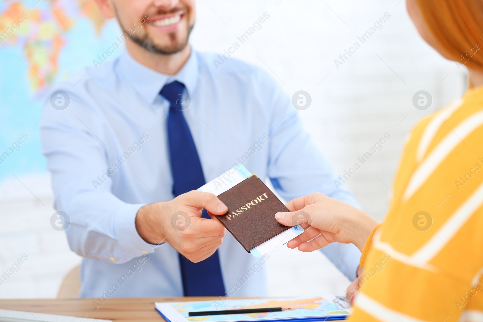 Photo of Male manager giving passport with ticket to client in travel agency, closeup