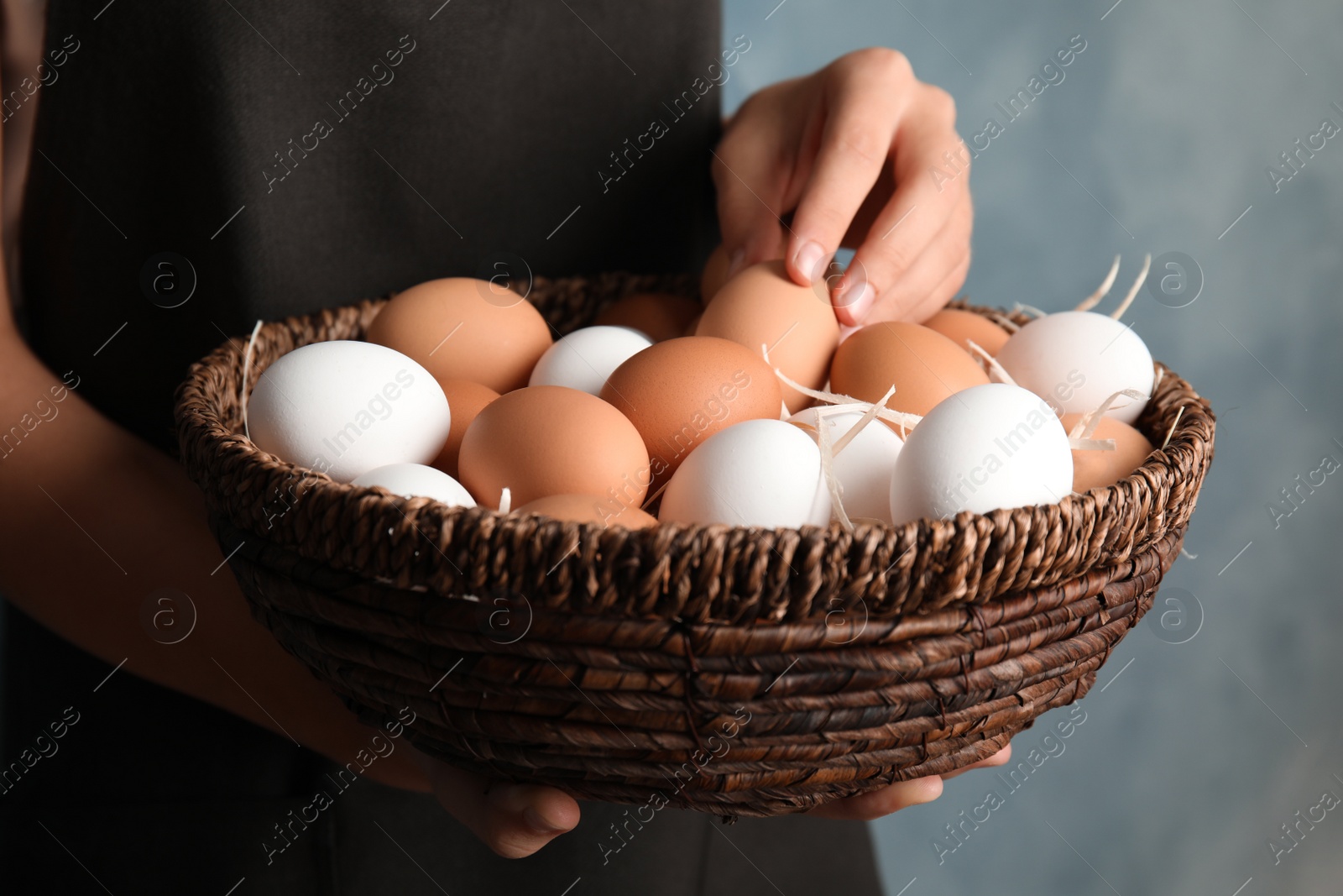 Photo of Woman with basket full of raw chicken eggs, closeup