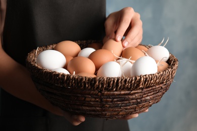 Photo of Woman with basket full of raw chicken eggs, closeup