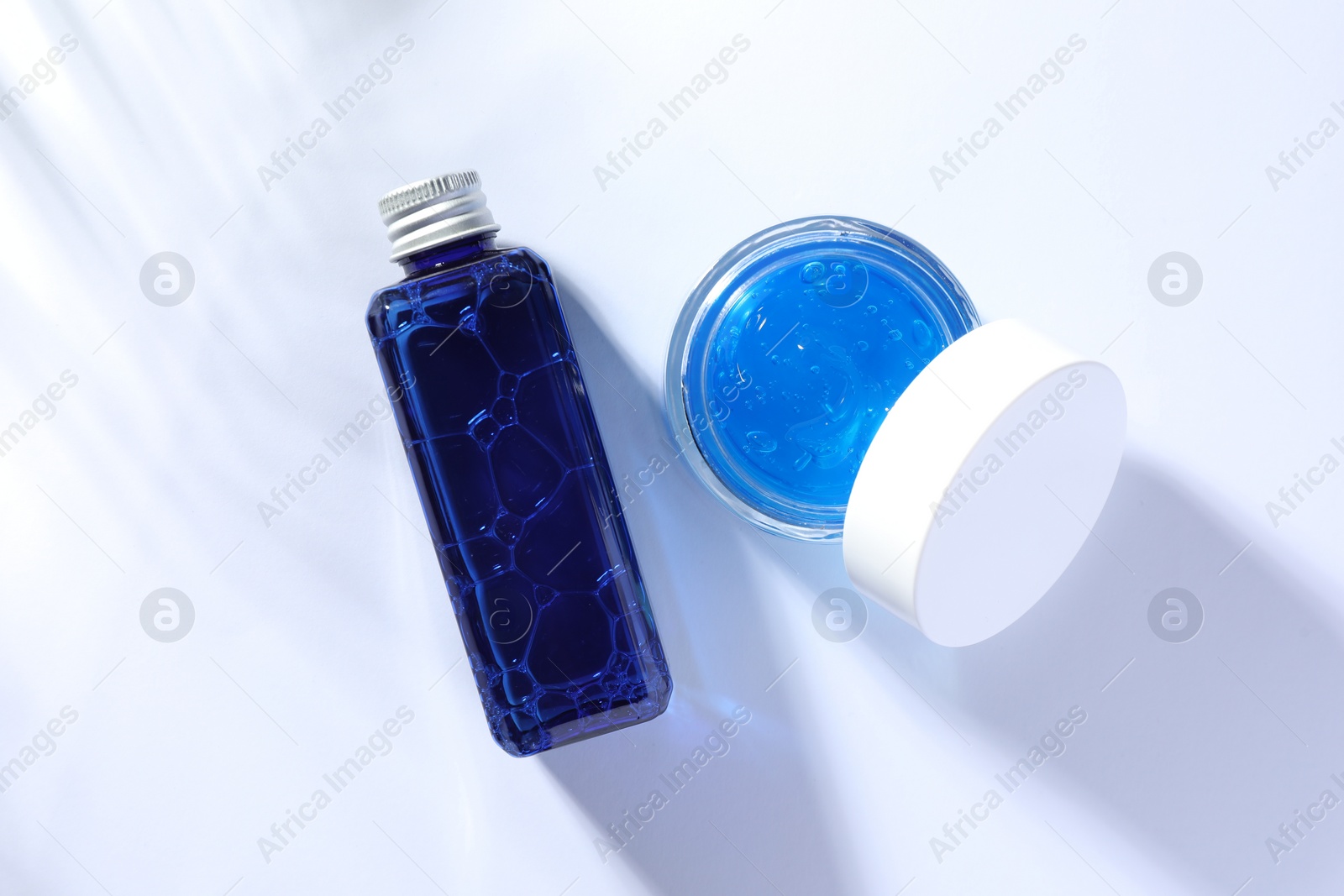 Photo of Bottle and jar of cosmetic products on white background, flat lay