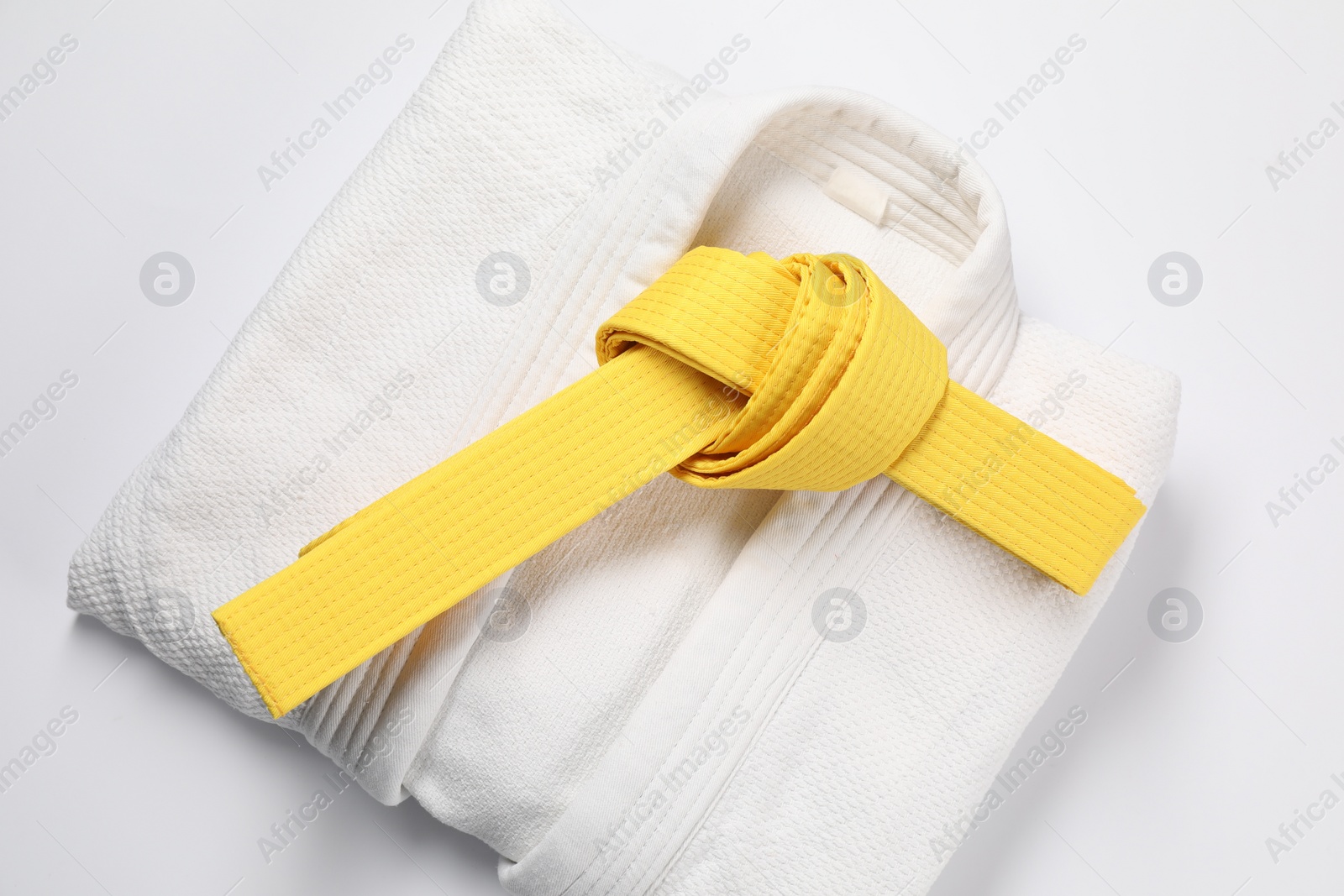 Photo of Yellow karate belt and kimono on white background, top view