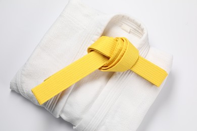 Photo of Yellow karate belt and kimono on white background, top view