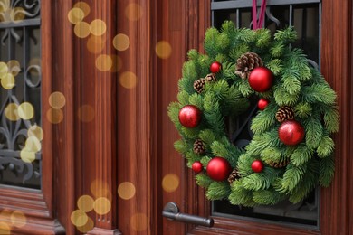 Photo of Beautiful Christmas wreath hanging on wooden door, space for text