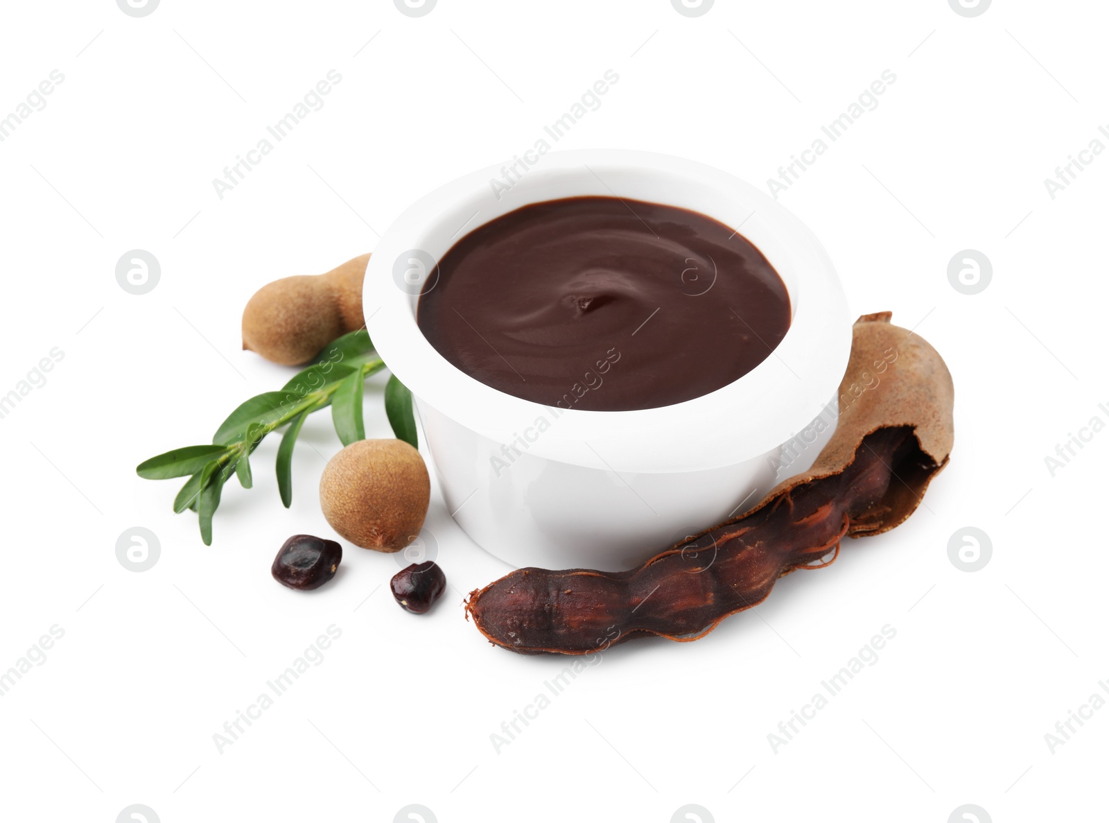 Bowl of tasty tamarind sauce, leaves and fresh pods isolated on white Photo of Bowl of tasty tamarind sauce, leaves and fresh pods isolated on white