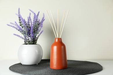 Aromatic reed air freshener and lavender flowers on white table. Space for text