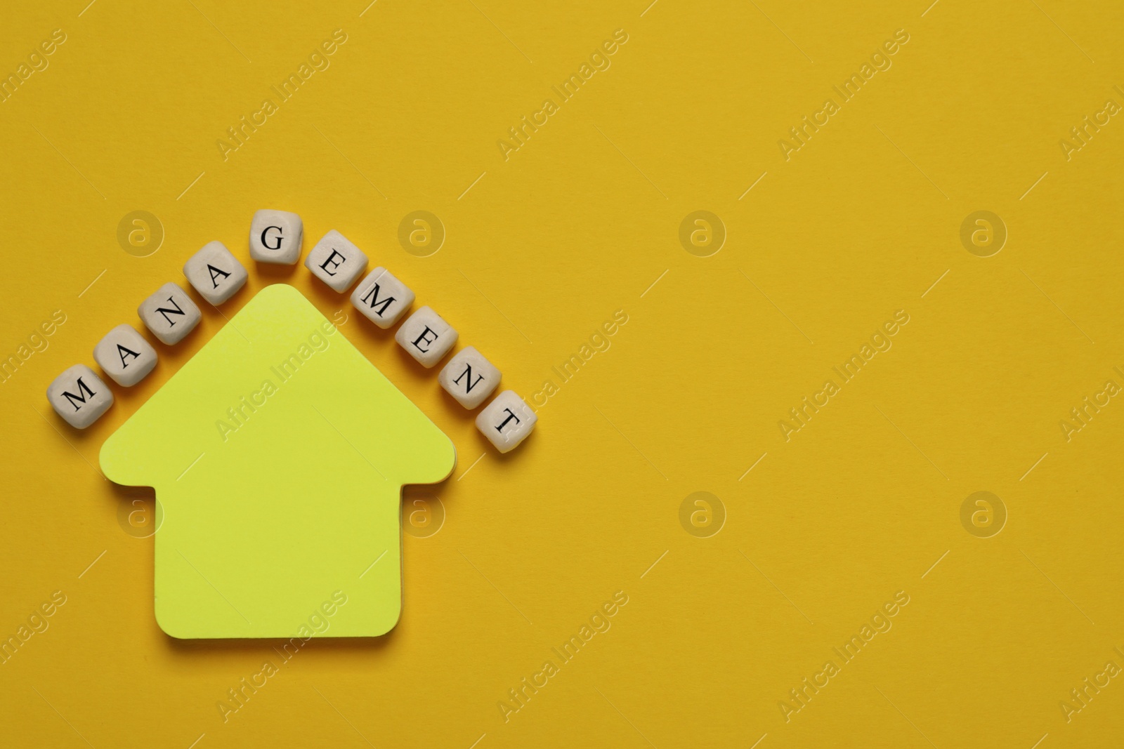 Photo of Word Management made of wooden cubes near arrow shaped paper note on yellow background, flat lay. Space for text