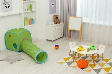 Photo of Child`s playroom with different toys and modern furniture. Stylish kindergarten interior