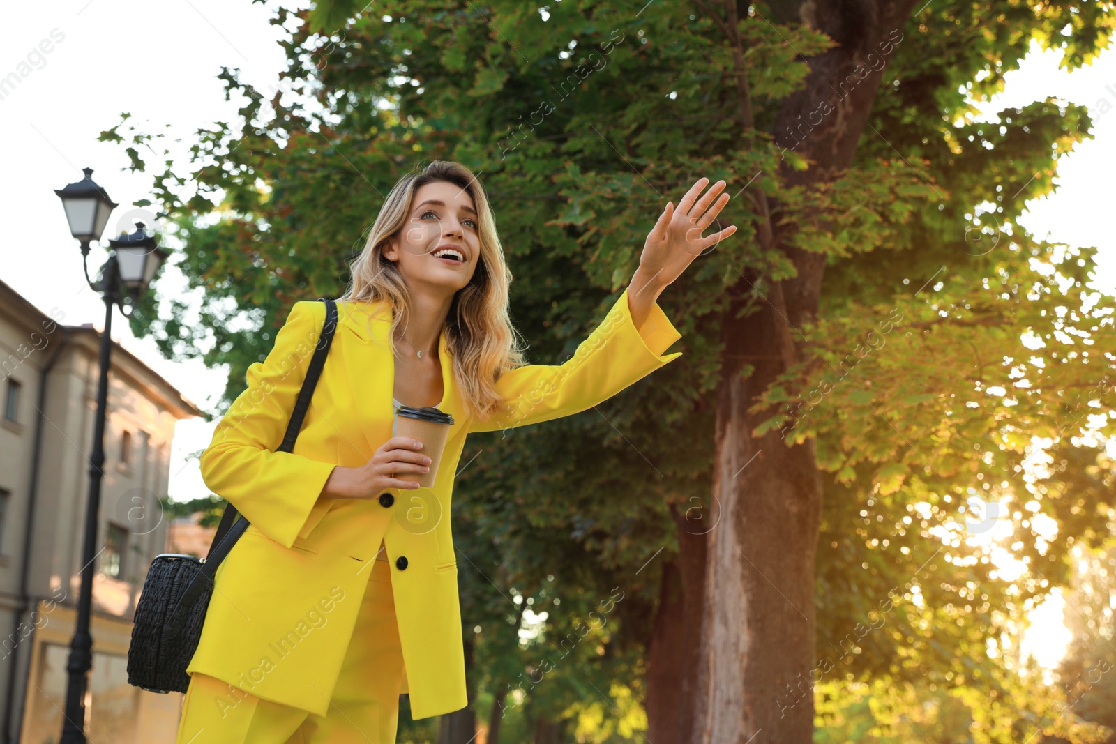 Photo of Young businesswoman catching taxi on city street