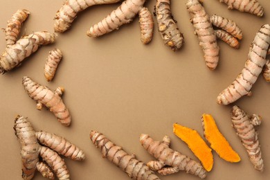 Photo of Many raw turmeric roots on light brown table, flat lay. Space for text