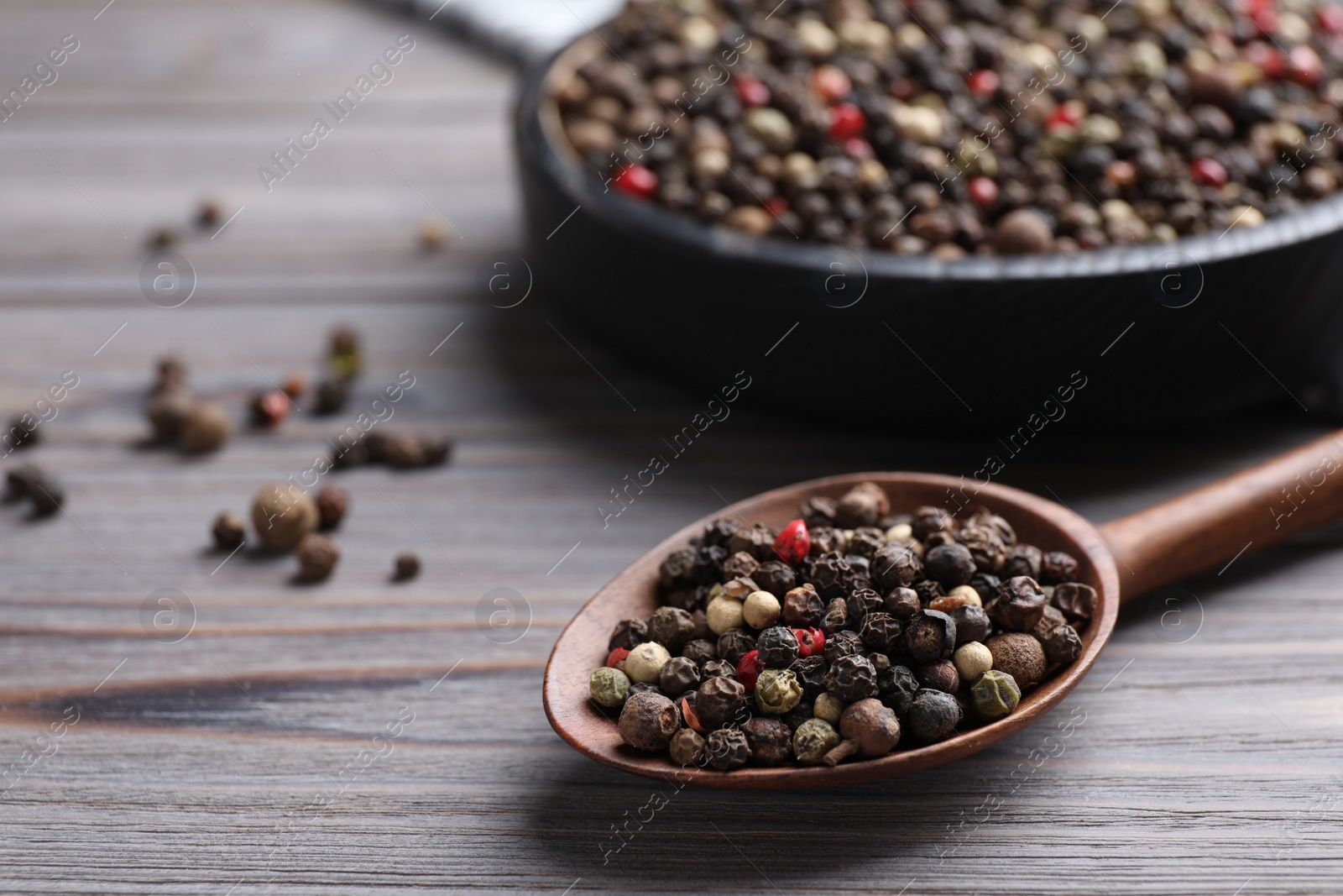 Photo of Different peppercorns on light grey wooden table, closeup