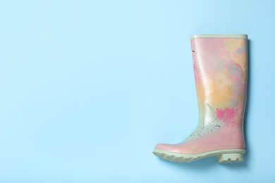 Photo of Colorful rubber boot on light blue background, top view. Space for text