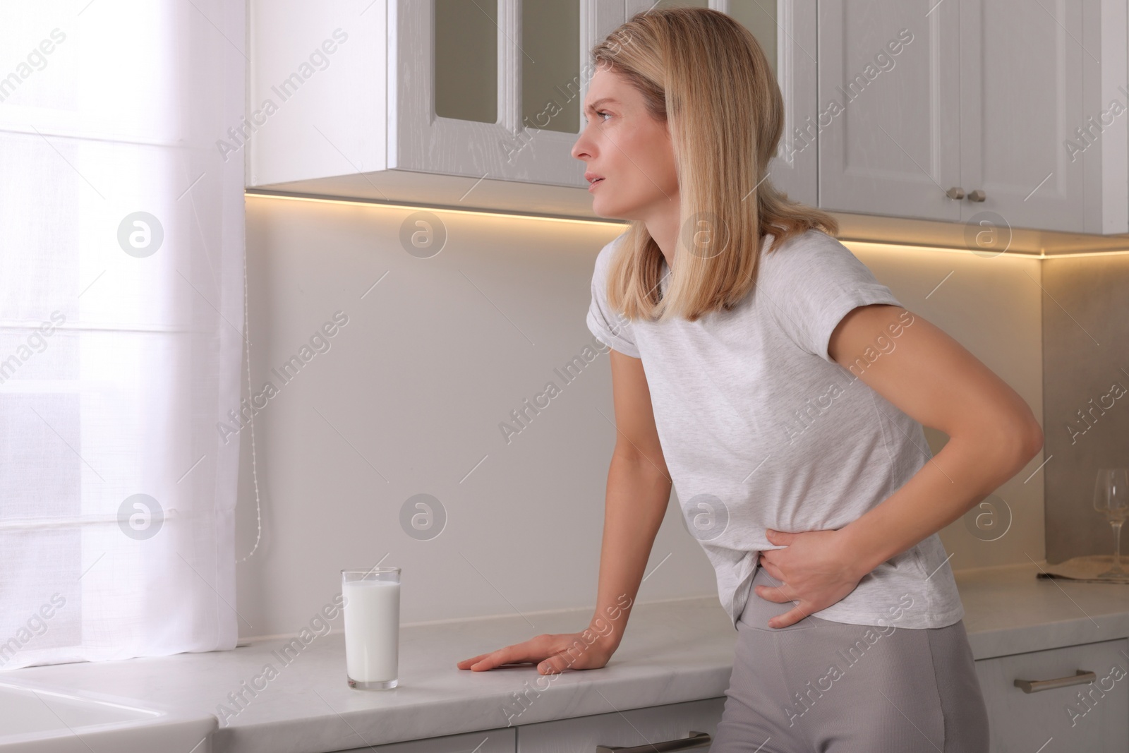 Photo of Woman suffering from lactose intolerance in kitchen
