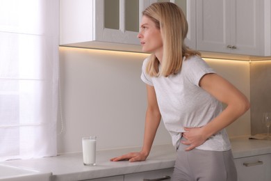 Woman suffering from lactose intolerance in kitchen