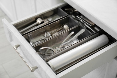 Photo of Open drawer with different utensils in kitchen, closeup