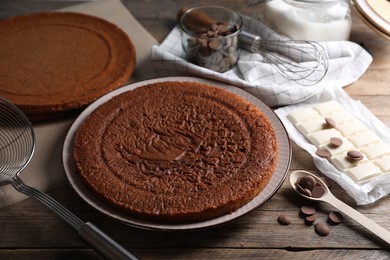 Delicious homemade sponge cake and different kinds of chocolate on wooden table, closeup