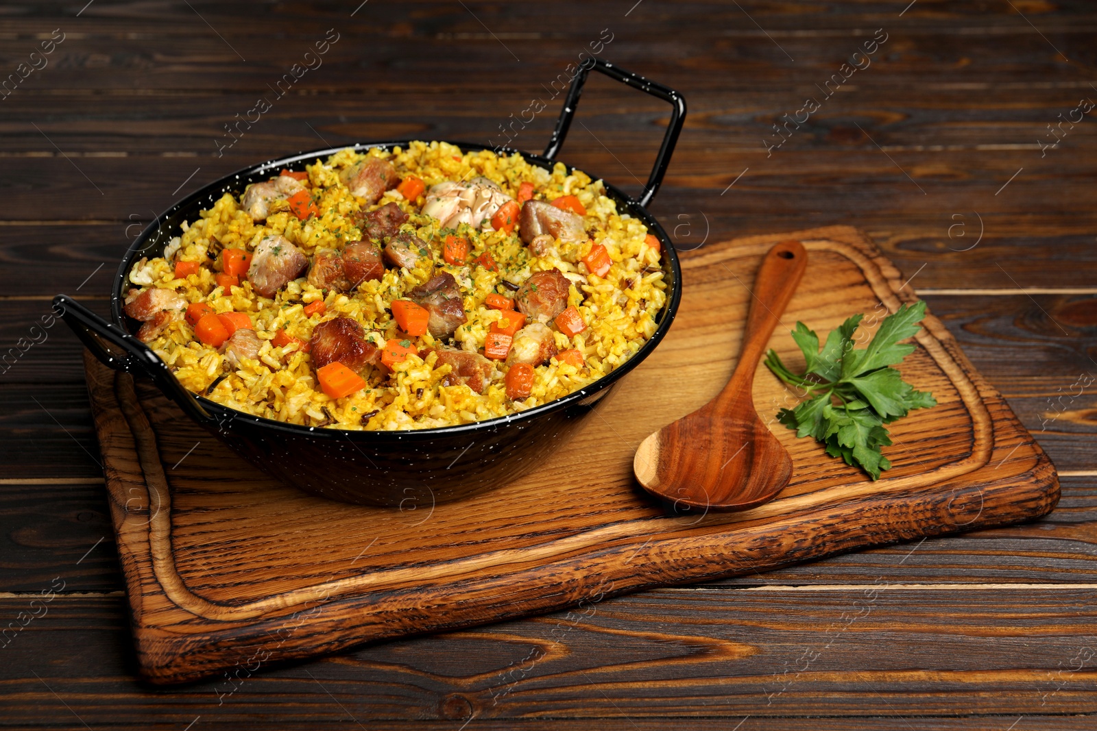 Photo of Delicious pilaf with meat, carrot and garlic served on wooden table