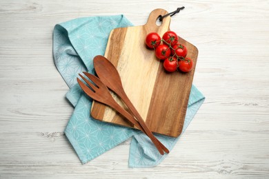 Photo of Cutting board, tomatoes and cooking utensils on white wooden table, flat lay