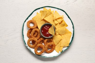 Photo of Tasty tortilla and fried onion rings with ketchup on white wooden table, top view