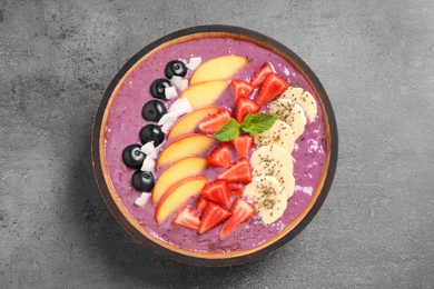 Photo of Delicious acai smoothie with fresh fruits on grey table, top view