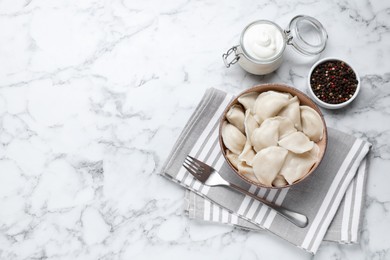 Photo of Tasty dumplings in bowl served on white marble table, flat lay. Space for text