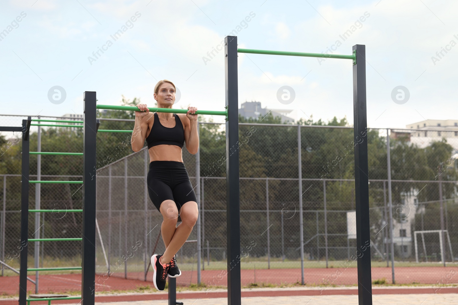 Photo of Woman doing pull ups at outdoor gym, space for text