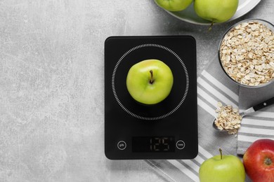 Digital kitchen scale, apples and oat flakes on grey table, flat lay. Space for text