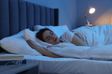 Beautiful young woman sleeping in bed at night