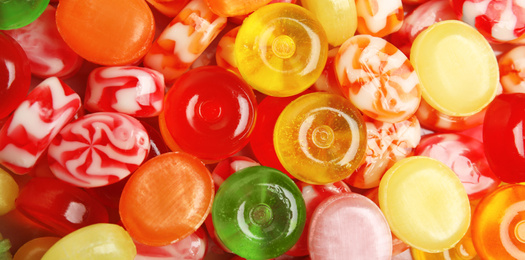 Different delicious colorful candies as background, top view. Banner design 