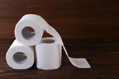 Photo of Many soft toilet paper rolls on wooden table. Space for text