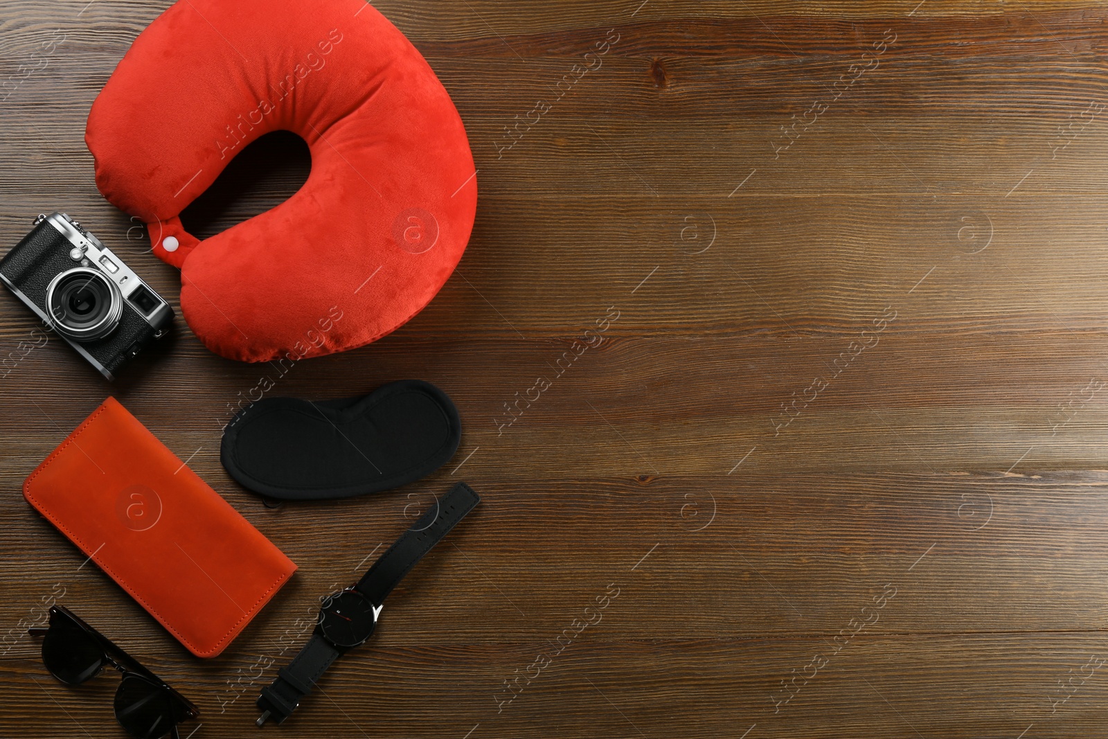 Photo of Flat lay composition with travel pillow and tourist stuff on wooden background. Space for text