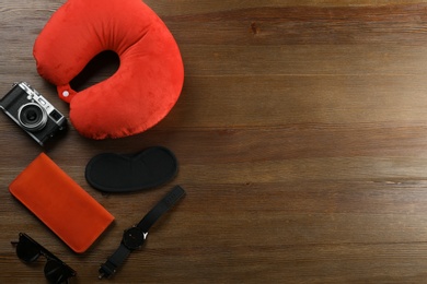 Photo of Flat lay composition with travel pillow and tourist stuff on wooden background. Space for text