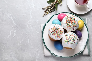 Photo of Traditional Easter cakes and painted eggs on light grey table, flat lay. Space for text