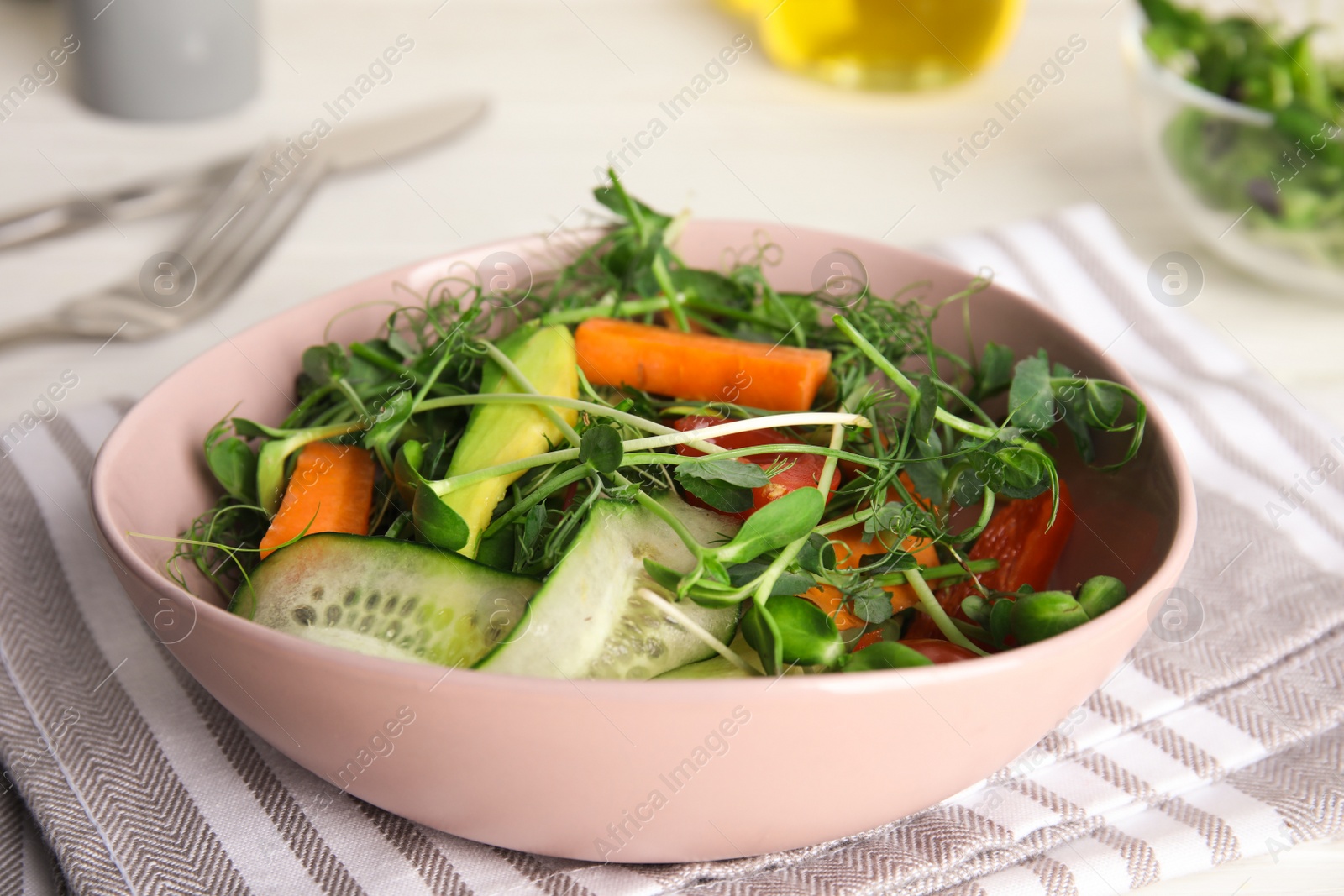 Photo of Salad with fresh organic microgreen in bowl on white table, closeup