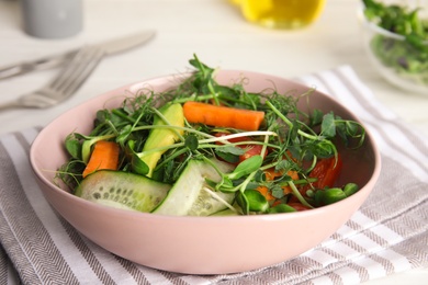 Photo of Salad with fresh organic microgreen in bowl on white table, closeup