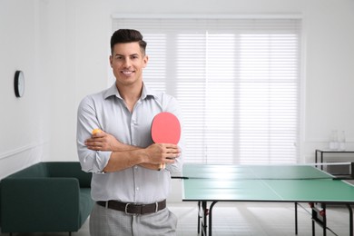 Photo of Businessman with tennis racket and ball near ping pong table in office. Space for text
