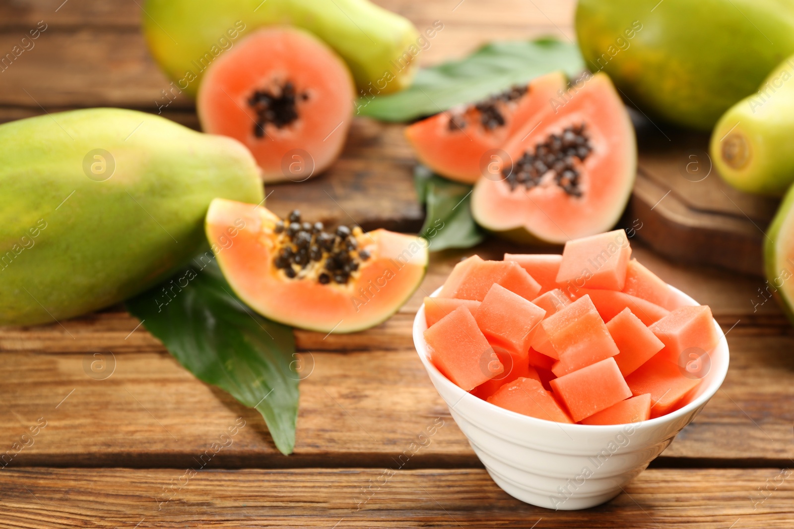 Photo of Fresh diced papaya fruit in bowl on wooden table
