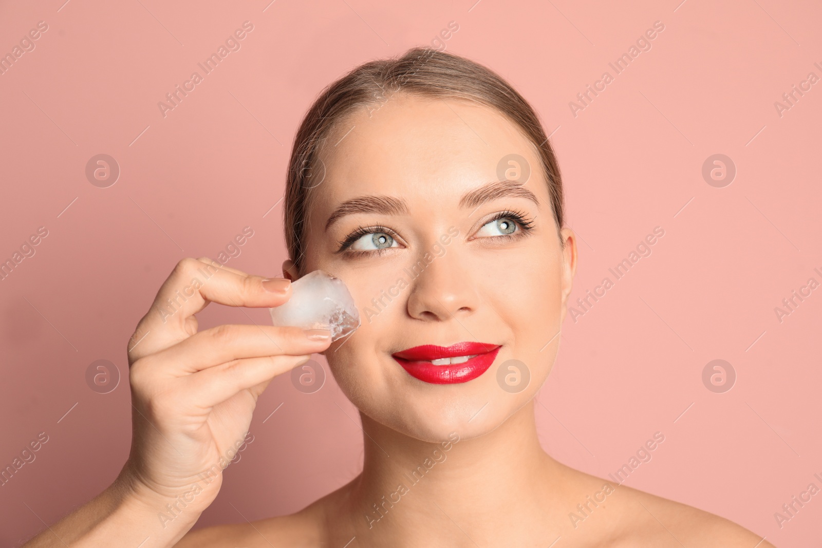 Photo of Young woman with ice cube on color background. Skin care