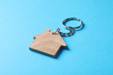 Photo of Wooden keychain in shape of house on light blue background