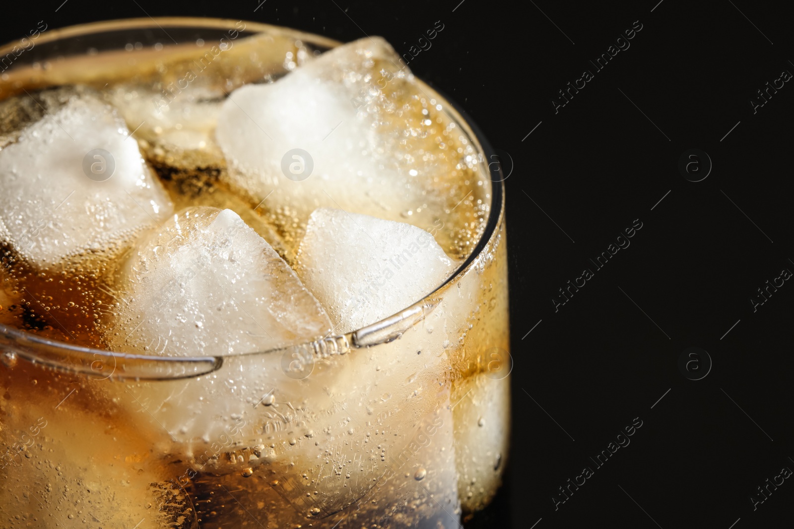 Photo of Glass of refreshing soda drink with ice cubes on black background, closeup