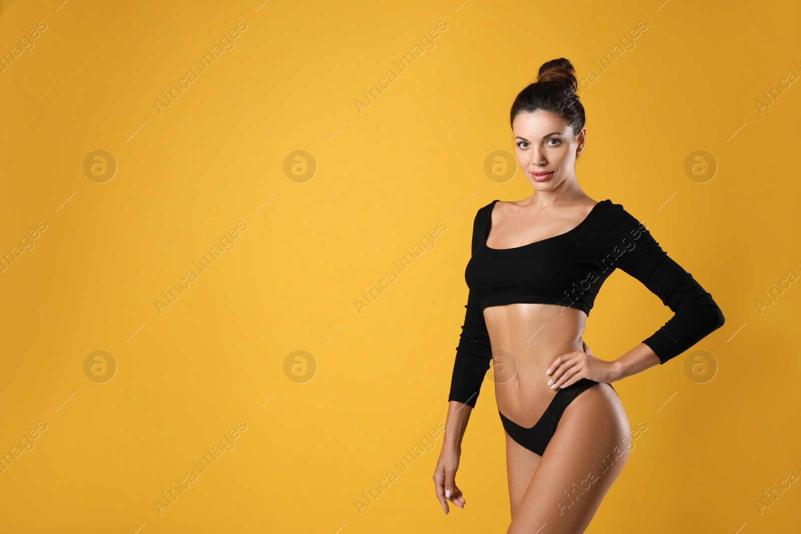 Photo of Beautiful woman in black sexy panties on yellow background, space for text