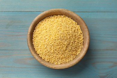 Photo of Millet groats in bowl on light blue wooden table, top view