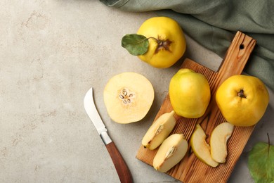 Photo of Tasty ripe quince fruits and knife on grey table, flat lay. Space for text