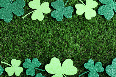 Frame made of clover leaves on green grass, flat lay with space for text. St. Patrick's Day celebration