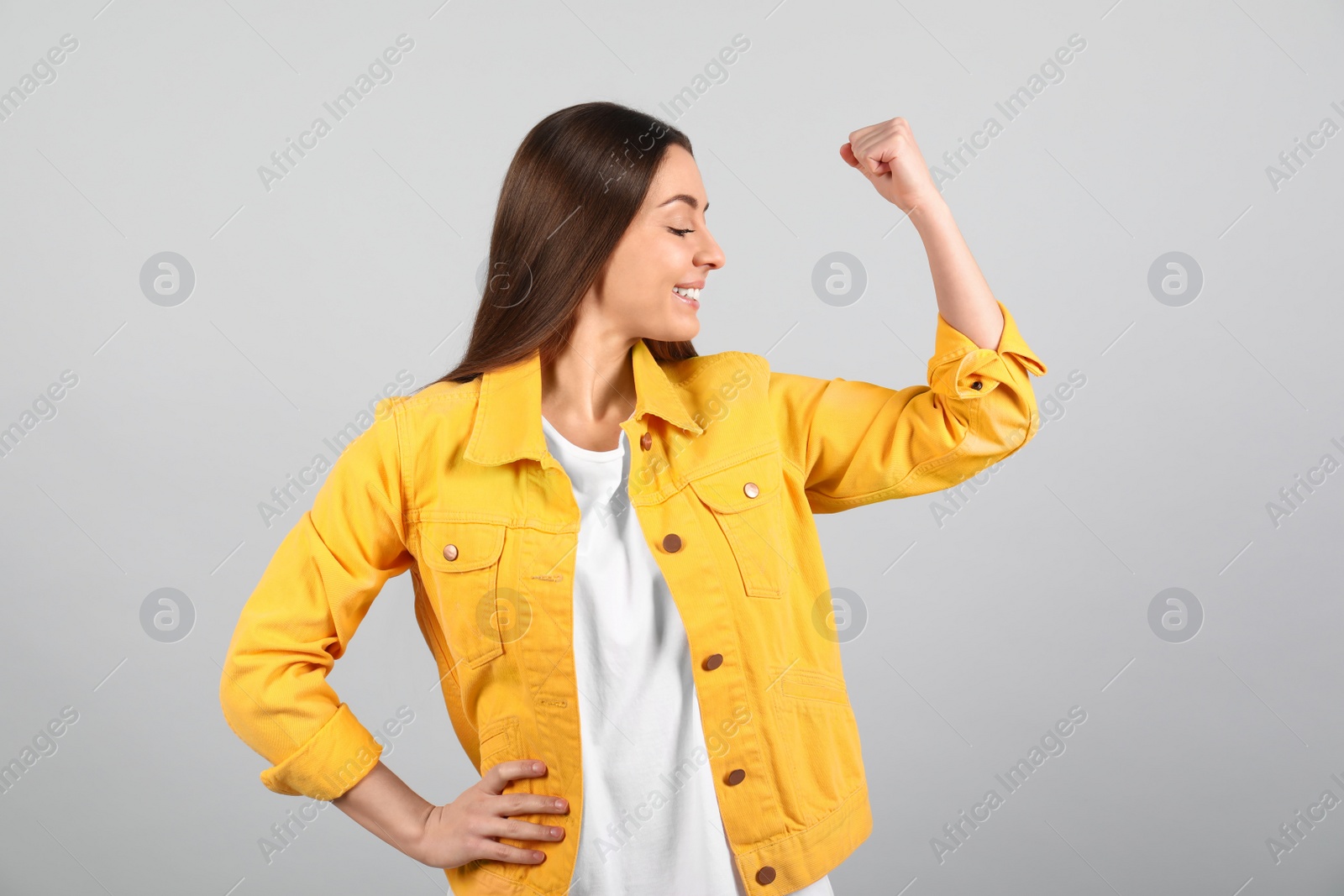 Photo of Strong woman as symbol of girl power on light grey background. 8 March concept